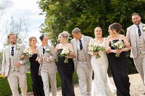 Wedding party walking whilst holding bridal bouquets and wearing buttonholes